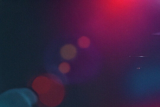 Abstract colorful bokeh lights on a dark background with soft red, pink, purple, and blue glow. Vibrant defocused light texture for modern design, atmosphere, and creative visual effects