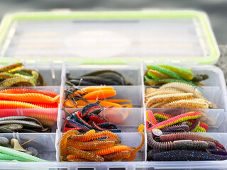 Colorful rubber lures for predatory fish, pike and walleye in a plastic box. Plastic fishing tackle...