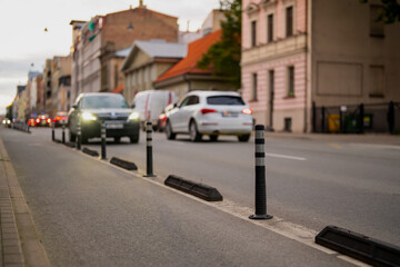 Cars driving along renovated urban street with lane dividers and safety barriers in evening light representing modern city transport infrastructure and traffic organization
