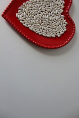 Young, raw white beans in a red ceramic bowl. Isolated on a white background. Flat lay. Copy space below.