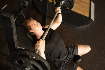Fototapeta premium Sporty caucasian man or bodybuilder exercising bench press at fitness center. Male athlete lifting weights.