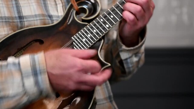 closeup of male hands playing bluegrass f style traditional mandolin