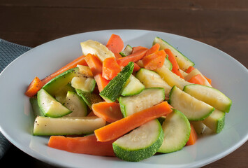 Carrot pieces and cooked squash on a white plate for preparation or combination with food
