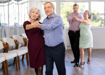 Couple of mature woman and male partner waltzes during party for single people. Entertaining hobby, learning dance moves.