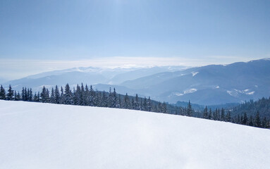 Snowy mountain landscape with forest and blue sky