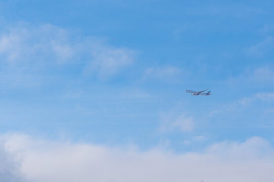 Commercial airplane approaching Frankfurt Airport, photographed from Hochheim am Main in Germany &ndash; aircraft in flight with landing gear down against cloudy sky, aviation and travel concept