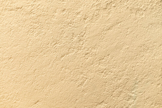 Detalle frontal de muro mexicano pintado de color crema o arena, textura. Concreto decorado con acabado rustico y cacarizo. Pared antigua tradicional con dise&ntilde;o de la epoca colonial.