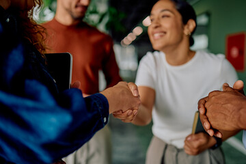 Diverse business partners are shaking hands at an office meeting, symbolizing agreement,...
