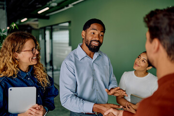 Multiracial business partners establishing trust and closing a deal with a handshake, showing teamwork in a modern office