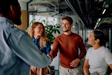 Diverse business professionals smiling, shaking hands, and networking in a modern corporate office environment