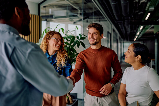 Diverse business professionals smiling, shaking hands, and networking in a modern corporate office environment