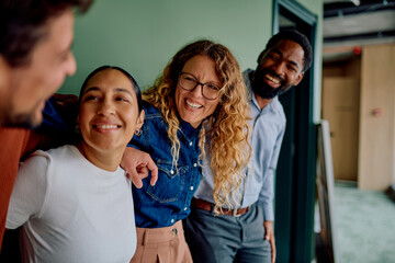 Diverse business friends smiling and laughing together, demonstrating camaraderie and positive teamwork in an office environment