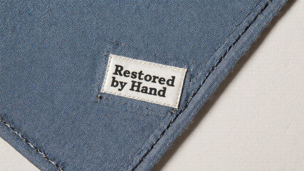 Restored by hand tag sewn on soft dark blue fabric with fine stitching