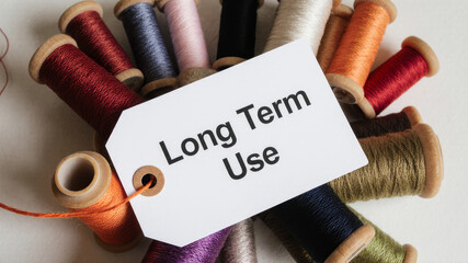 Long term use tag tied to thread spool on soft textile background