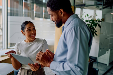 Diverse colleagues actively discussing professional strategy, collaborating and communicating using a tablet in a modern corporate office setting