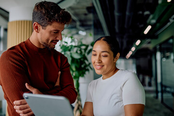 Diverse business colleagues collaborating, discussing project plans, and networking using a digital tablet in a modern office workplace