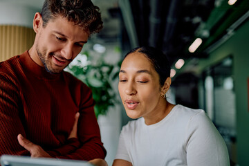 Business colleagues collaborating on digital tablet, discussing ideas and planning project strategies in a modern office environment