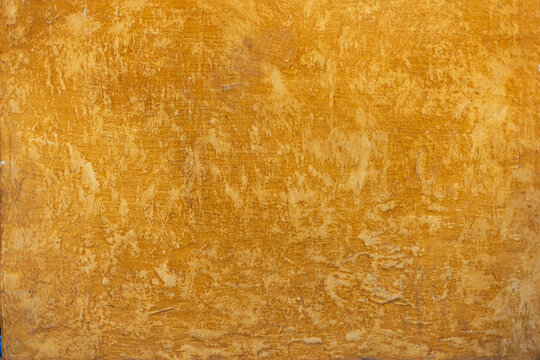 Detalle frontal de muro pintado color ocre o mostaza vibrante, textura y desgaste natural. Concreto decorado con acabado rustico. Pared antigua tradicional mexicana con dise&ntilde;o de la epoca colonial.