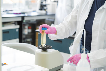 Scientist using vortex mixer with conical test tube in laboratory