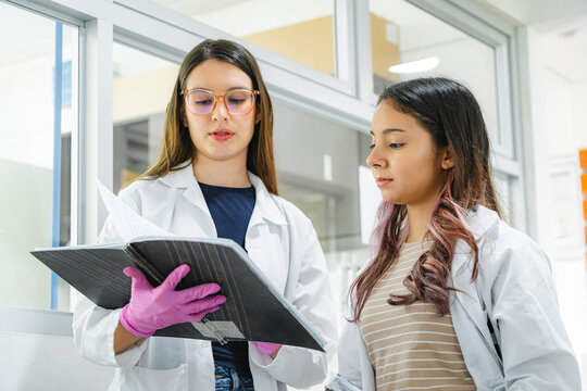 Female scientists reviewing lab notes in modern laboratory setting
