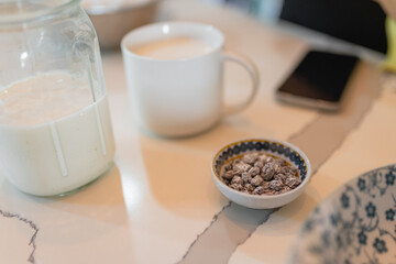 Close up of milk jar cup and seeds on kitchen table