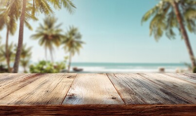 Wooden table sitting on top of a beach next to the ocean, surrounded by lush plants and trees. The sky is filled with white, fluffy clouds, creating a peaceful atmosphere.
