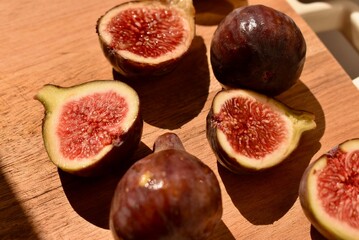 Sliced ripe fig on rustic wooden board. Natural fruit texture and seeds visible in detail. Healthy organic food concept.