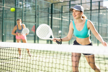 Active young woman practicing Padel Tennis with other player in the tennis court outdoors