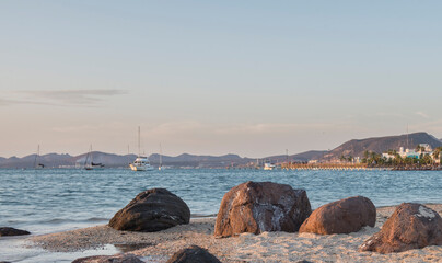 Sunset in La Paz Bay, Baja California Sur, Mexico, with rocks on the white sand of the beach, with...