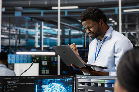 Angry engineer in data center annoyed by errors affecting equipment while using artificial intelligence computerized model. Irked server room employee frustrated by broken AI deep learning algorithms