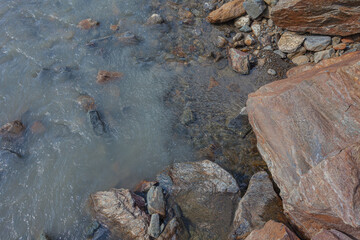Contact between transparent water and cloudy water in a glacial stream, Alto Adige, Italy