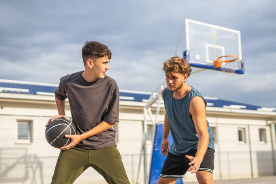 Young men playing basketball on outdoor court - Powered by Adobe