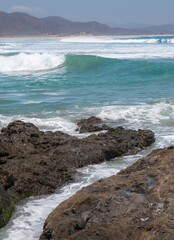 Los Cerritos Beach, Todos Santos, La Paz, Baja California Sur, Mexico, overlooking the Pacific Ocean with waves ideal for local surfers and foreign vacationers. with rocks in the foreground vertical 