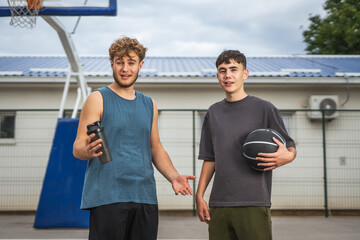 Male friends pausing during outdoor basketball game
