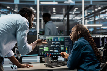 Data center software developers programming equipment used for machine learning training. Server room IT specialists talking, running code on PC to upgrade artificial intelligence systems