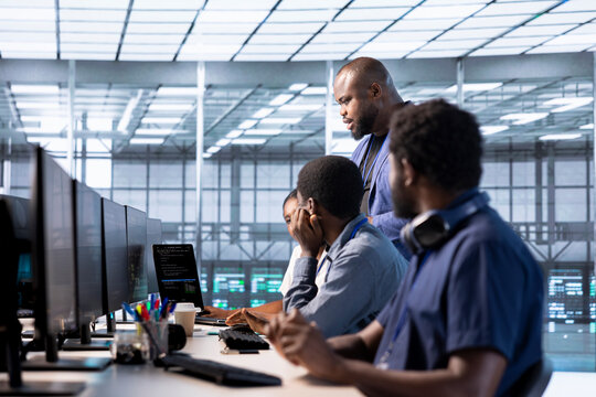 Team of data center office system administrators using programming languages to construct algorithms and build applications. African american server farm IT professionals debugging and optimizing code