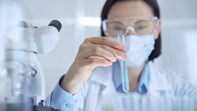 Scientist female researcher with protective glasses and mask exa
