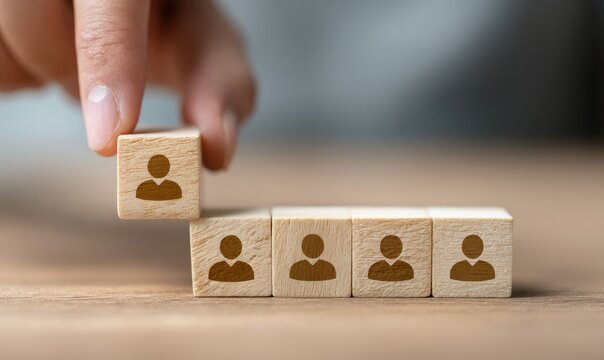 A hand places a wooden block featuring a person icon on top of a row of similar blocks