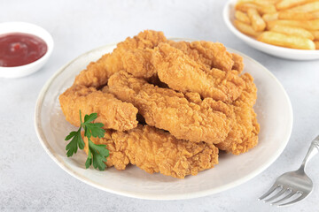 Crispy chicken strips with ketchup and French fries on a white background. Fast food. 