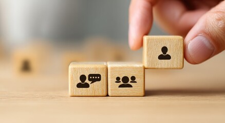 Hand placing a wooden block with a person icon, forming a step-like structure with other blocks featuring icons of people and a chat bubble