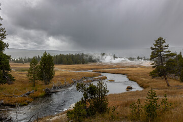 Explore Yellowstone's moody landscape, where a winding river meets geothermal steam under a...