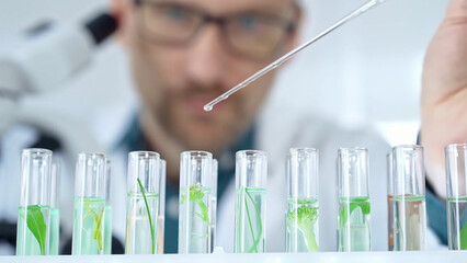 Man researcher with safety glasses is working with lab tubes using a pipette in laboratory, close-up of lab equipment. Science and medicine