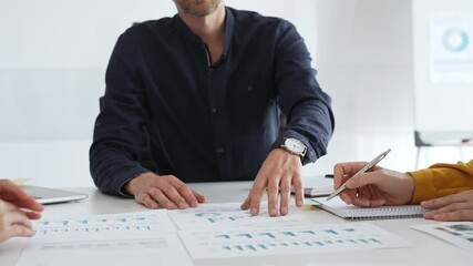 Professional colleagues reviewing financial charts, collaborating on strategic planning, gesturing toward data visualizations during corporate meeting in office. Business people concept - Powered by Adobe