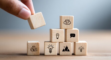 Wooden blocks stacked in a pyramid shape, with icons. A hand is placing a block on top
