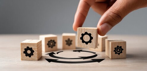 A hand places a small wooden block with a gear icon on top of other blocks, forming a circular pattern with arrows