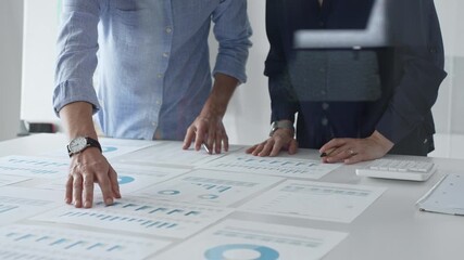 Professional team reviewing financial documents, pointing at charts on desk, collaborating to analyze data and strategize business growth. Business people concept - Powered by Adobe