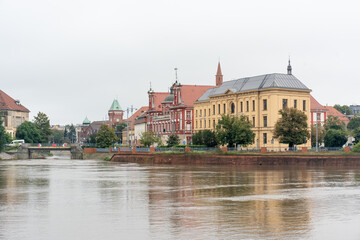 View of the river during floods in a historic European city with colourful architecture and overcast sky after rain. Concept of urban flooding, safety and emergency  