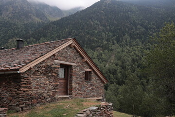 Rustic stone cabin nestled against a misty, forested mountain backdrop evokes peaceful solitude and...