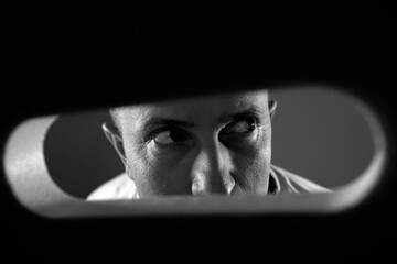 Mans eye looking through a blured keyhole

