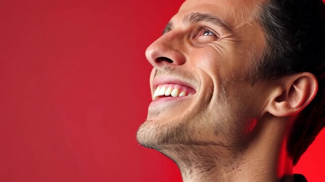 Joyful Reflection: A man&rsquo;s profile radiates with pure joy, capturing a moment of upward gaze against a vibrant red backdrop, embodying a sense of elation and optimism.